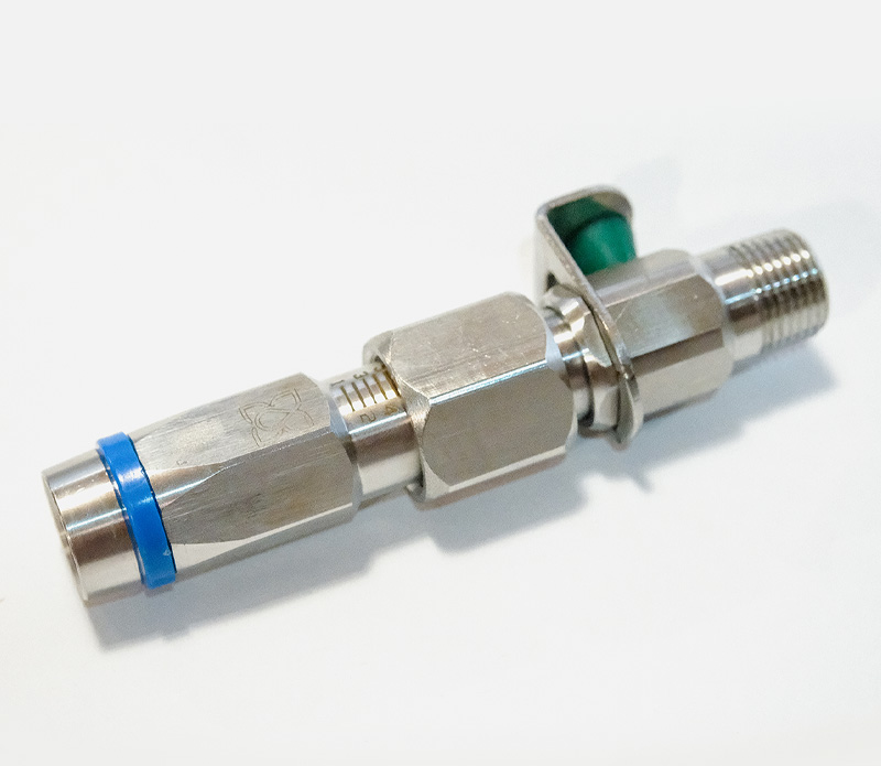 Racor de compresión neumático/hidráulico de metal con anillo de sellado azul y junta verde, sobre un fondo claro